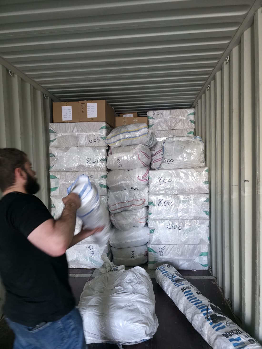 A REEMAS worker loading bales into the container